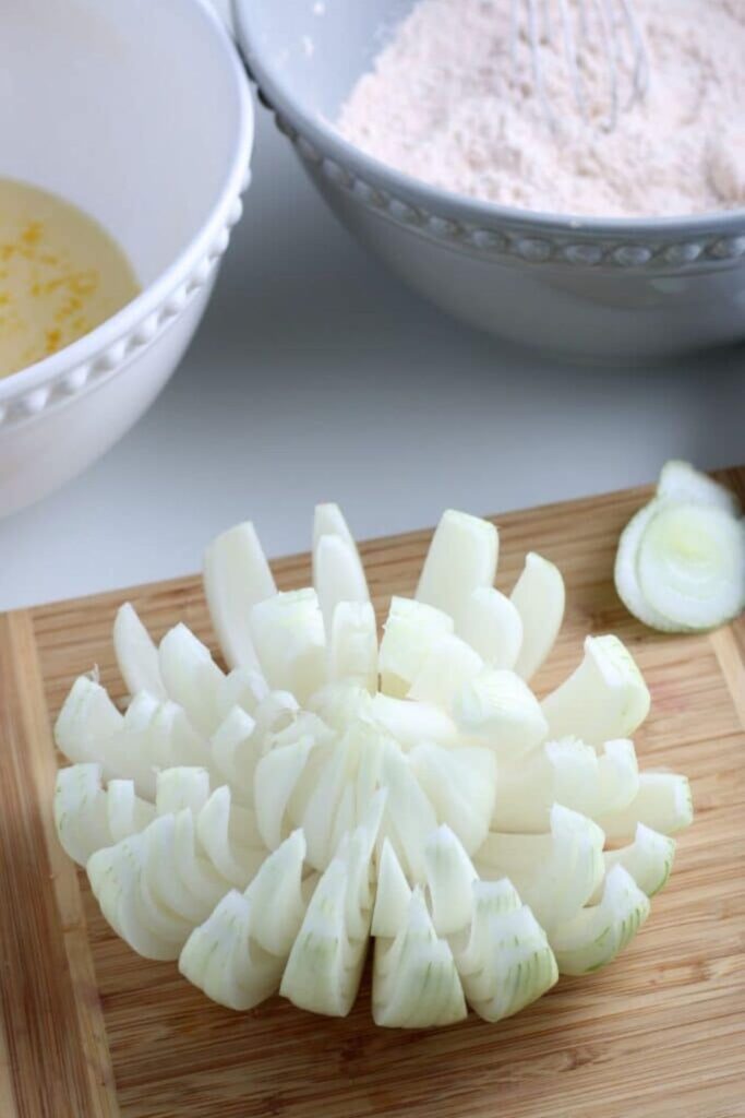 slices of onion shaped into a blooming onion on a cutting board