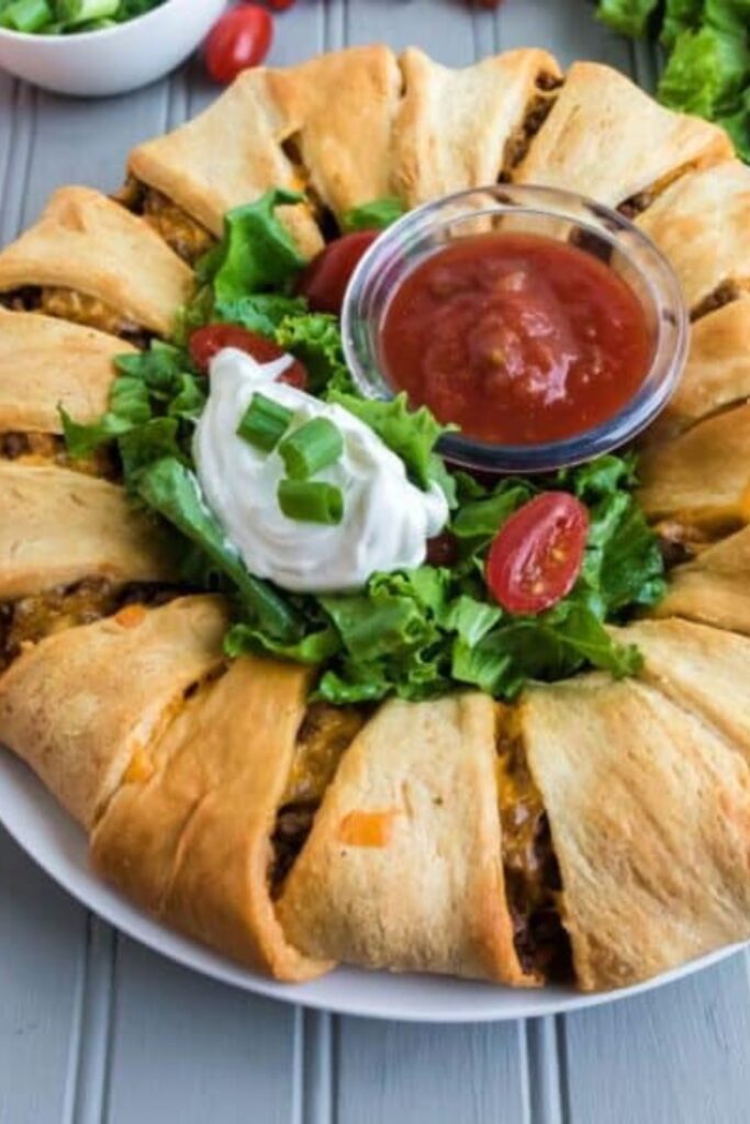 close up look of taco crescent ring on plate topped with cilantro, sour cream, and salsa
