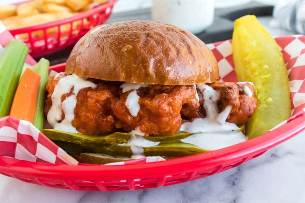 buffalo chicken sandwich in a basket with celery and carrots