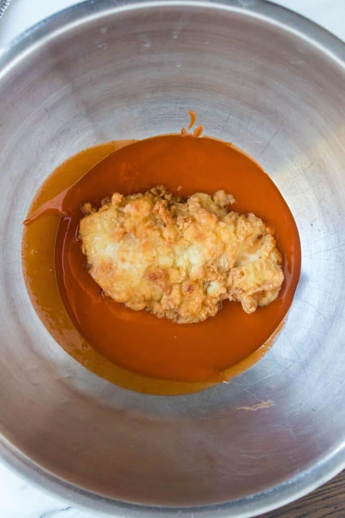 Buffalo Chicken in a metal bowl tossed with some sauce